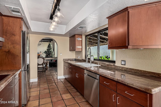 kitchen with sink, stainless steel appliances, a raised ceiling, pendant lighting, and a textured ceiling