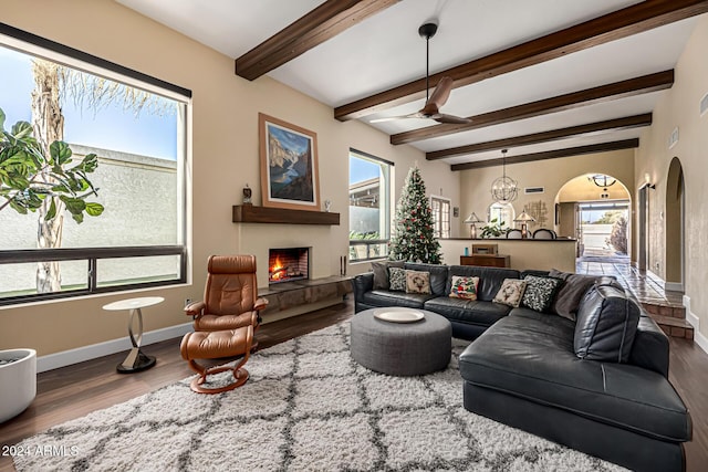 living room with beam ceiling, plenty of natural light, wood-type flooring, and ceiling fan with notable chandelier