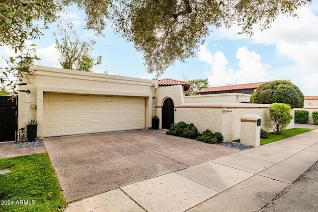 mediterranean / spanish-style house with driveway, a tiled roof, an attached garage, and stucco siding