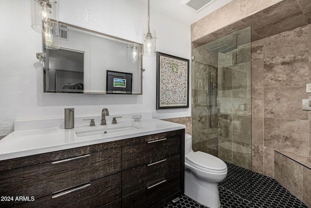 bathroom with a tile shower, tile patterned floors, vanity, and toilet