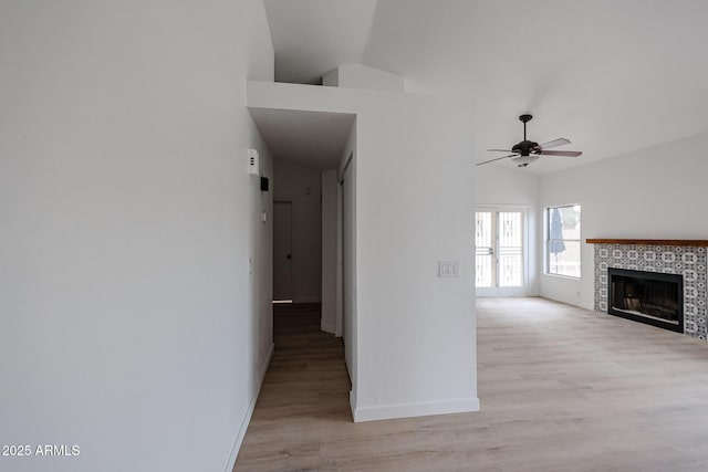 hall featuring baseboards, lofted ceiling, and light wood-style floors