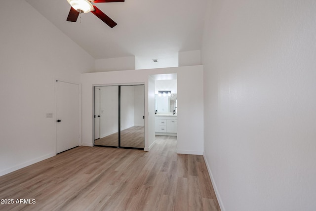 unfurnished bedroom with ensuite bath, ceiling fan, vaulted ceiling, a closet, and light wood-type flooring