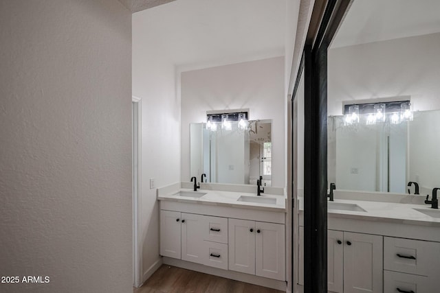 full bath featuring double vanity, a sink, and wood finished floors