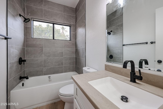 full bathroom featuring tiled shower / bath, vanity, and toilet