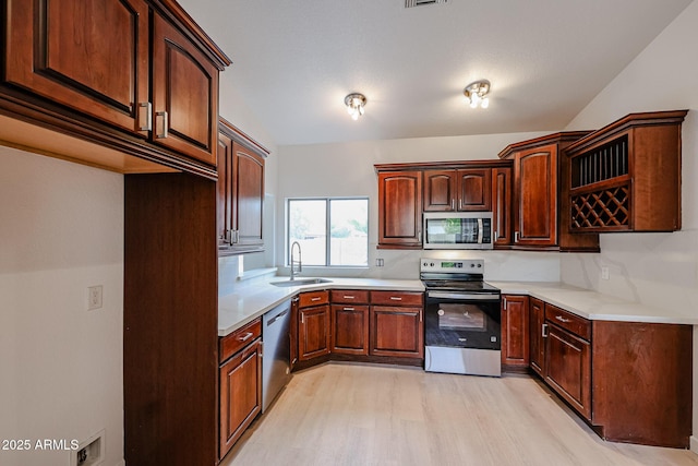 kitchen with light wood finished floors, light countertops, visible vents, appliances with stainless steel finishes, and a sink