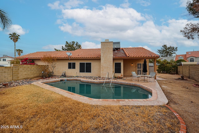 rear view of property with a fenced in pool, a yard, and a patio area