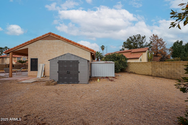 rear view of property featuring a patio and a storage unit