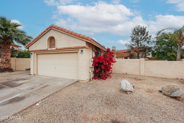 exterior space featuring an outbuilding, a tile roof, stucco siding, fence, and driveway