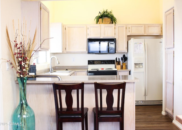 kitchen with a breakfast bar, sink, electric range oven, kitchen peninsula, and white fridge with ice dispenser