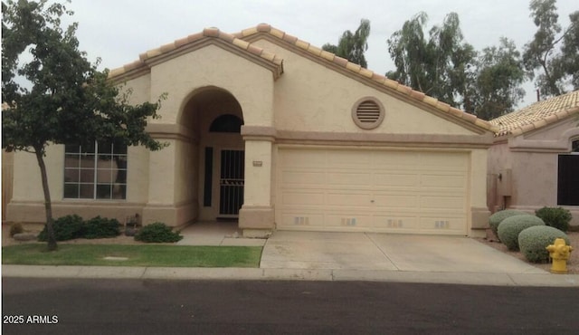 mediterranean / spanish house featuring a garage, concrete driveway, a tile roof, and stucco siding