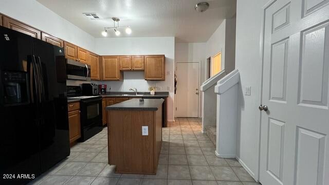 kitchen with sink, light tile patterned floors, black appliances, and a center island