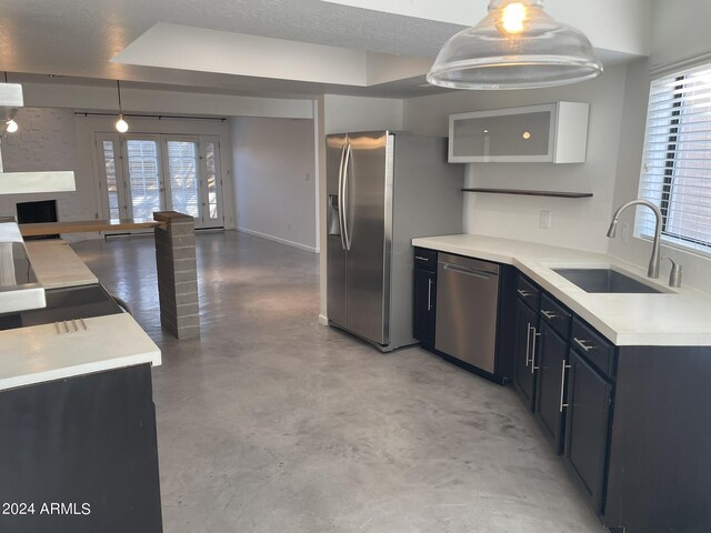 kitchen featuring concrete floors, appliances with stainless steel finishes, sink, pendant lighting, and a textured ceiling