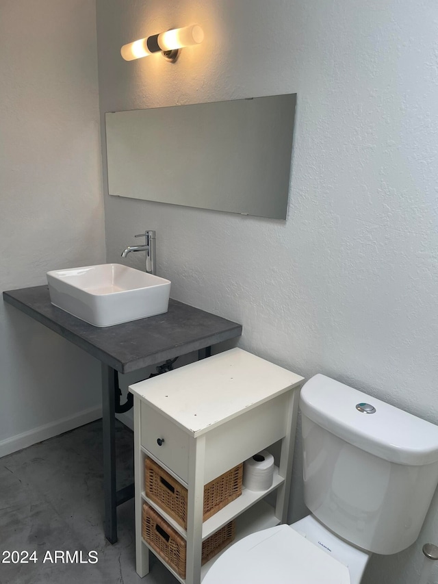 bathroom featuring concrete floors, toilet, and sink