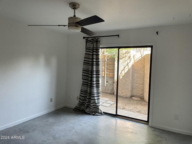 unfurnished room with ceiling fan and concrete flooring