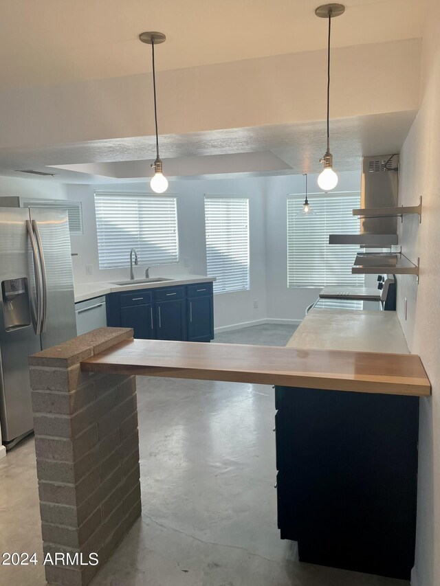 kitchen featuring appliances with stainless steel finishes, pendant lighting, blue cabinetry, and sink