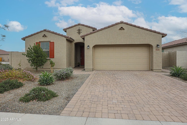 mediterranean / spanish home featuring a tiled roof, decorative driveway, a garage, and stucco siding