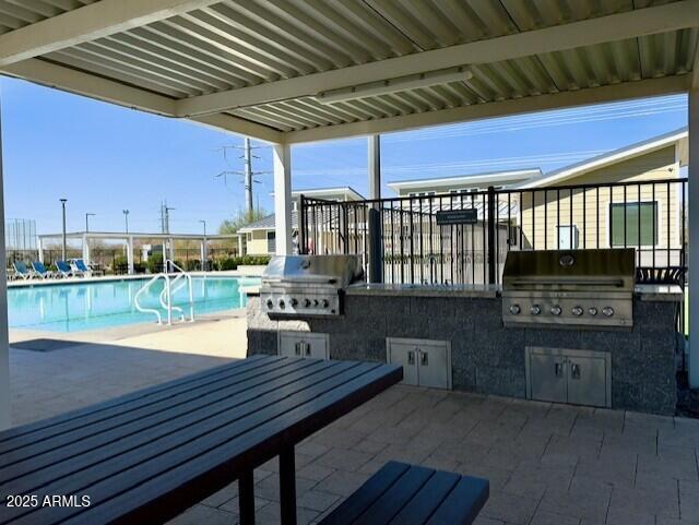 view of patio with grilling area, exterior kitchen, and a community pool