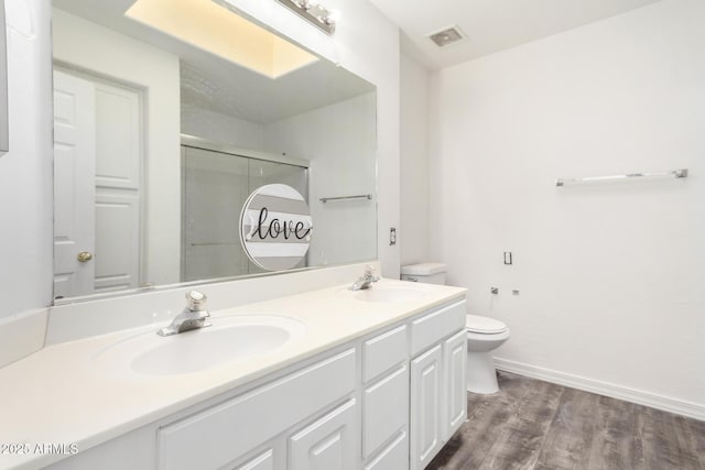 bathroom with vanity, hardwood / wood-style flooring, a shower with door, and toilet