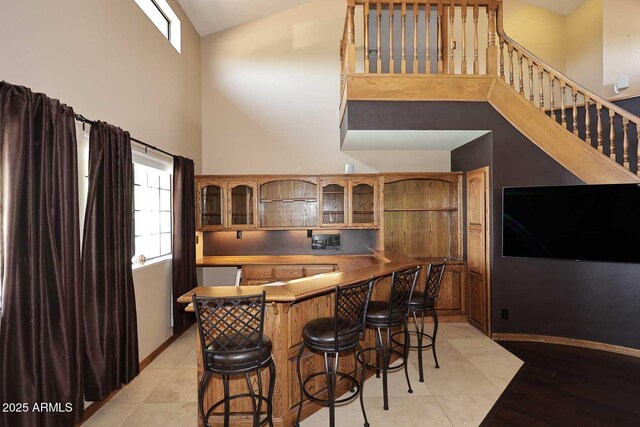11215 N Garland Cir, Fountain Hills, AZ 85268 - bar featuring high vaulted ceiling, baseboards, wet bar, light tile patterned floors, and stairway
