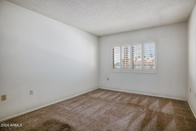 carpeted spare room featuring a textured ceiling