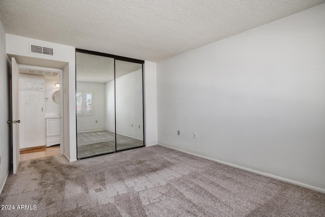 unfurnished bedroom featuring light carpet, a closet, and a textured ceiling