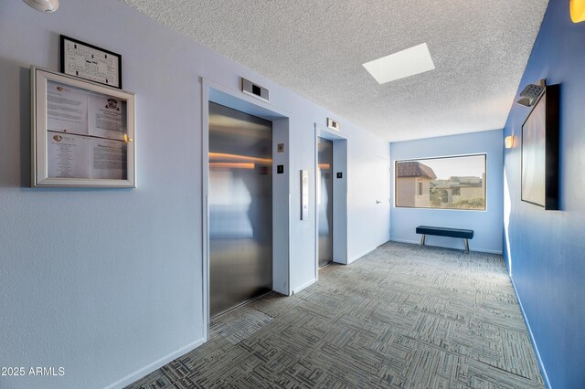 hall featuring a textured ceiling and elevator