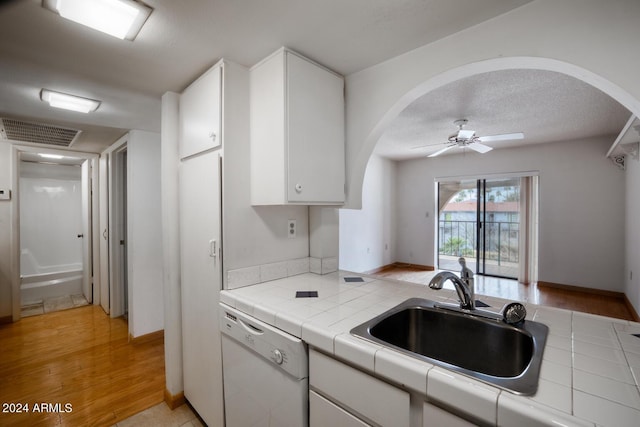 kitchen with sink, tile countertops, white dishwasher, light hardwood / wood-style floors, and white cabinets