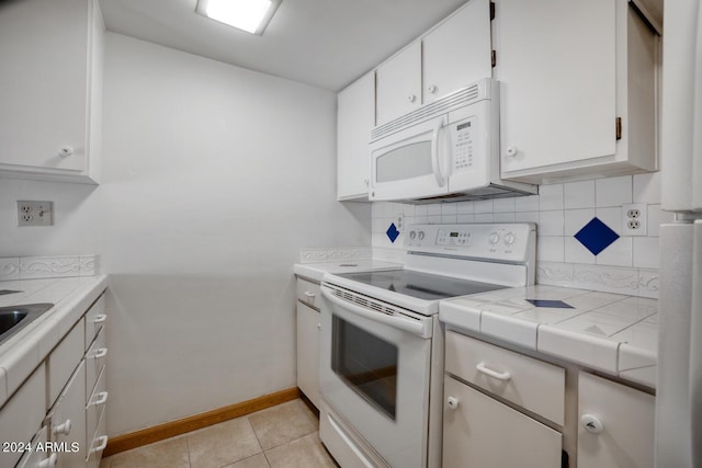 kitchen featuring tile countertops, white appliances, light tile patterned floors, tasteful backsplash, and white cabinetry