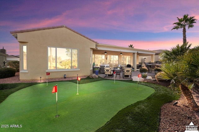 back house at dusk with a patio area and ceiling fan