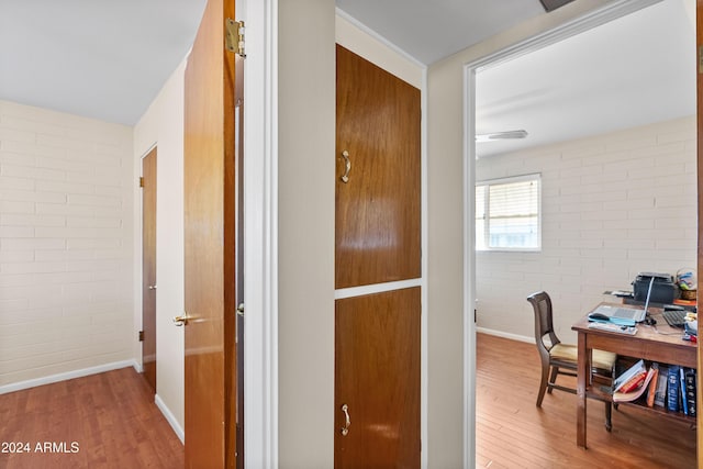 hall featuring hardwood / wood-style floors and brick wall