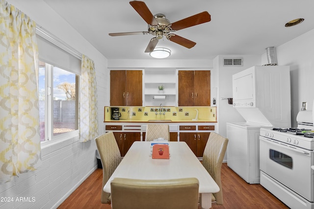 kitchen with dark hardwood / wood-style floors, stacked washer / dryer, white gas stove, and sink