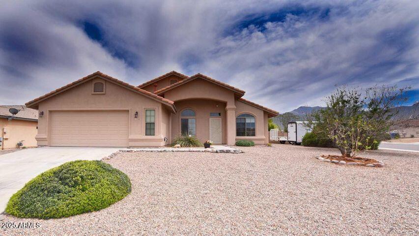 view of front of house with a garage, a tiled roof, concrete driveway, and stucco siding