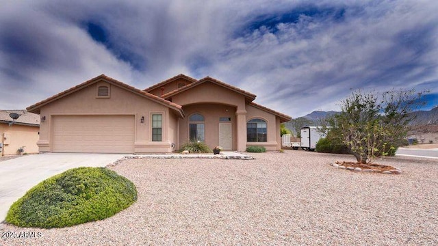 view of front of house with a garage, a tiled roof, concrete driveway, and stucco siding