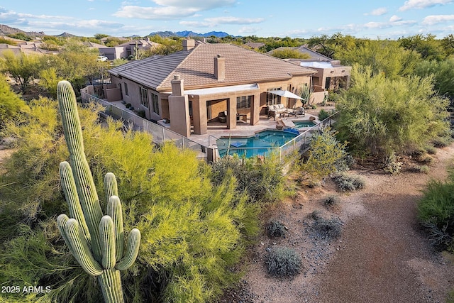 back of house with a patio, a fenced backyard, a tile roof, a pool with connected hot tub, and stucco siding