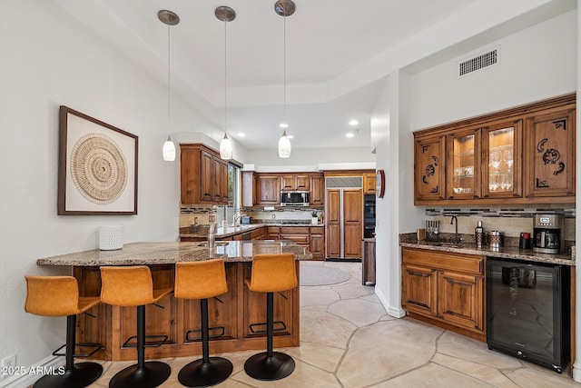 kitchen with paneled built in fridge, decorative backsplash, wine cooler, stainless steel microwave, and a peninsula