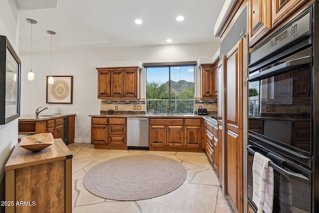 kitchen with dobule oven black, a sink, brown cabinets, dishwasher, and pendant lighting