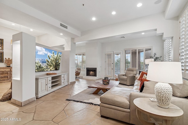 living area with baseboards, a lit fireplace, visible vents, and recessed lighting