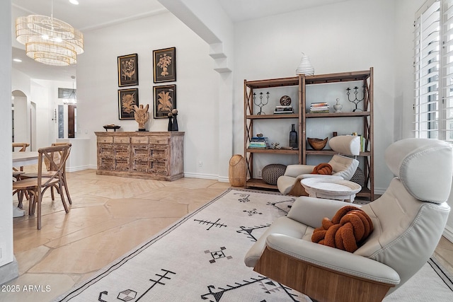 living area with a chandelier, arched walkways, and baseboards