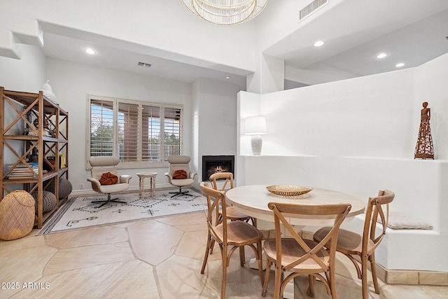 dining area featuring a warm lit fireplace, tile patterned flooring, visible vents, and recessed lighting