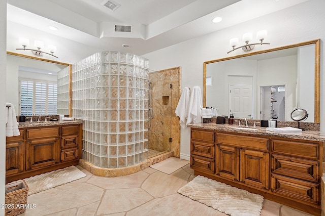 full bathroom with tile patterned flooring, visible vents, tiled shower, and vanity