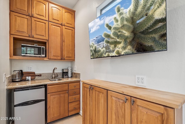 kitchen featuring refrigerator, a sink, wooden counters, brown cabinets, and stainless steel microwave