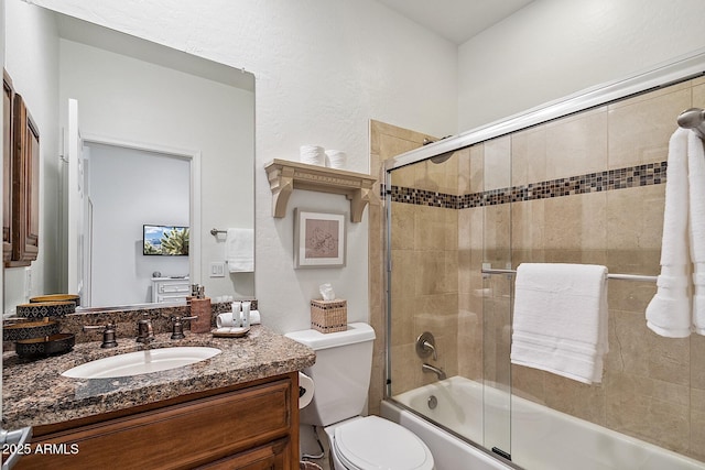 bathroom featuring toilet, combined bath / shower with glass door, and vanity