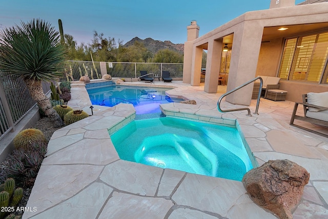 view of pool with a pool with connected hot tub, a patio area, fence, and a mountain view