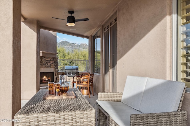 exterior space featuring an outdoor stone fireplace, grilling area, and a ceiling fan