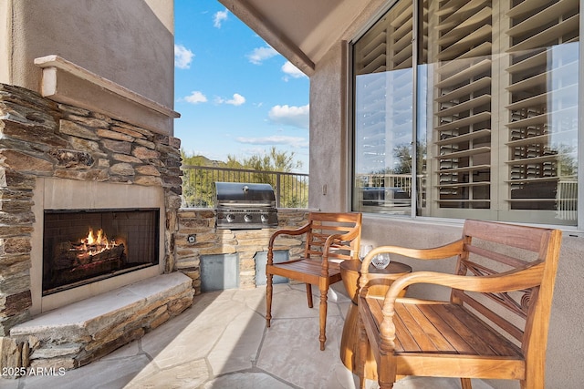 view of patio with an outdoor stone fireplace and a grill