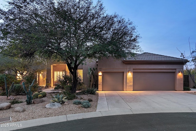 view of front of property with driveway, a tile roof, a garage, and stucco siding