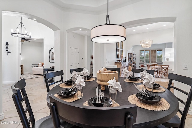 dining area with a towering ceiling, a chandelier, arched walkways, and recessed lighting