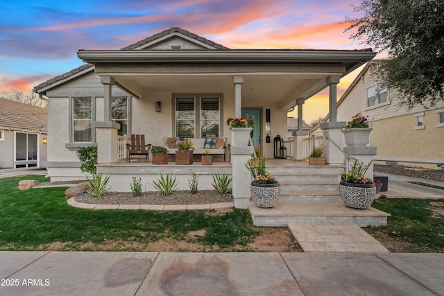 view of front of home with a porch, a tiled roof, and stucco siding