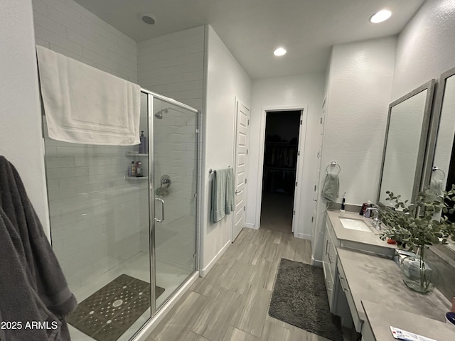 bathroom with wood-type flooring, vanity, and a shower with door