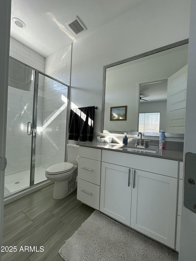 bathroom featuring hardwood / wood-style floors, vanity, toilet, and a shower with door